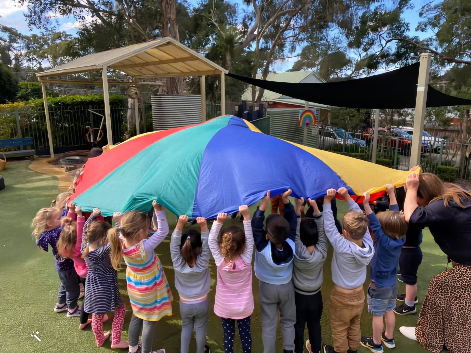 Children playing together under a colourful parachute